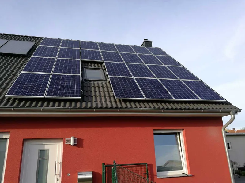 Rotes Wohnhaus mit Photovoltaikmodulen auf dem Dach